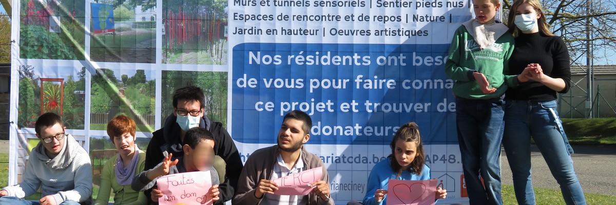 Un groupe de jeunes en situation de handicap posant devant un panneau publicitaire